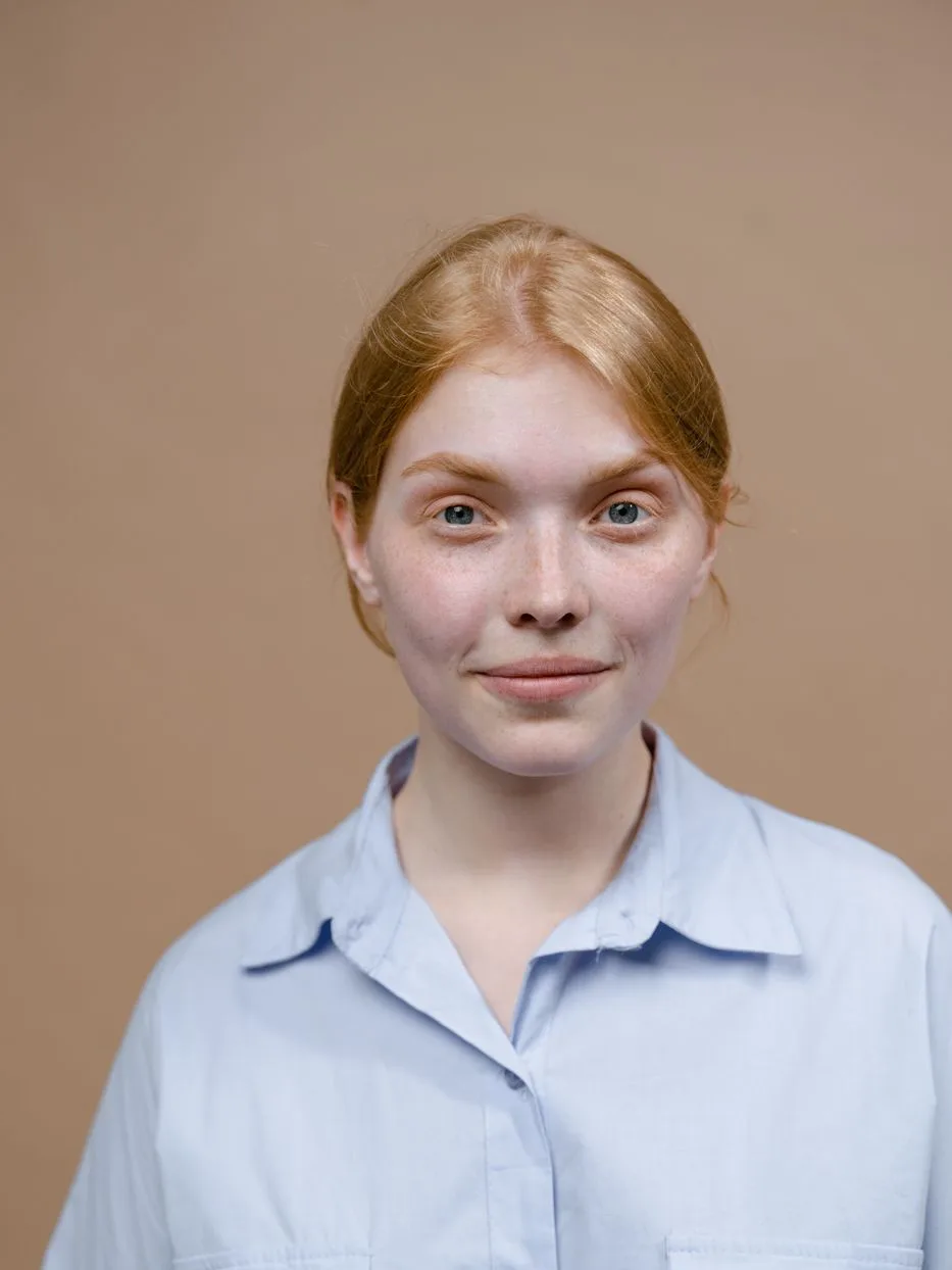 Sofia, massage therapist, in a pale blue shirt against a warm neutral background